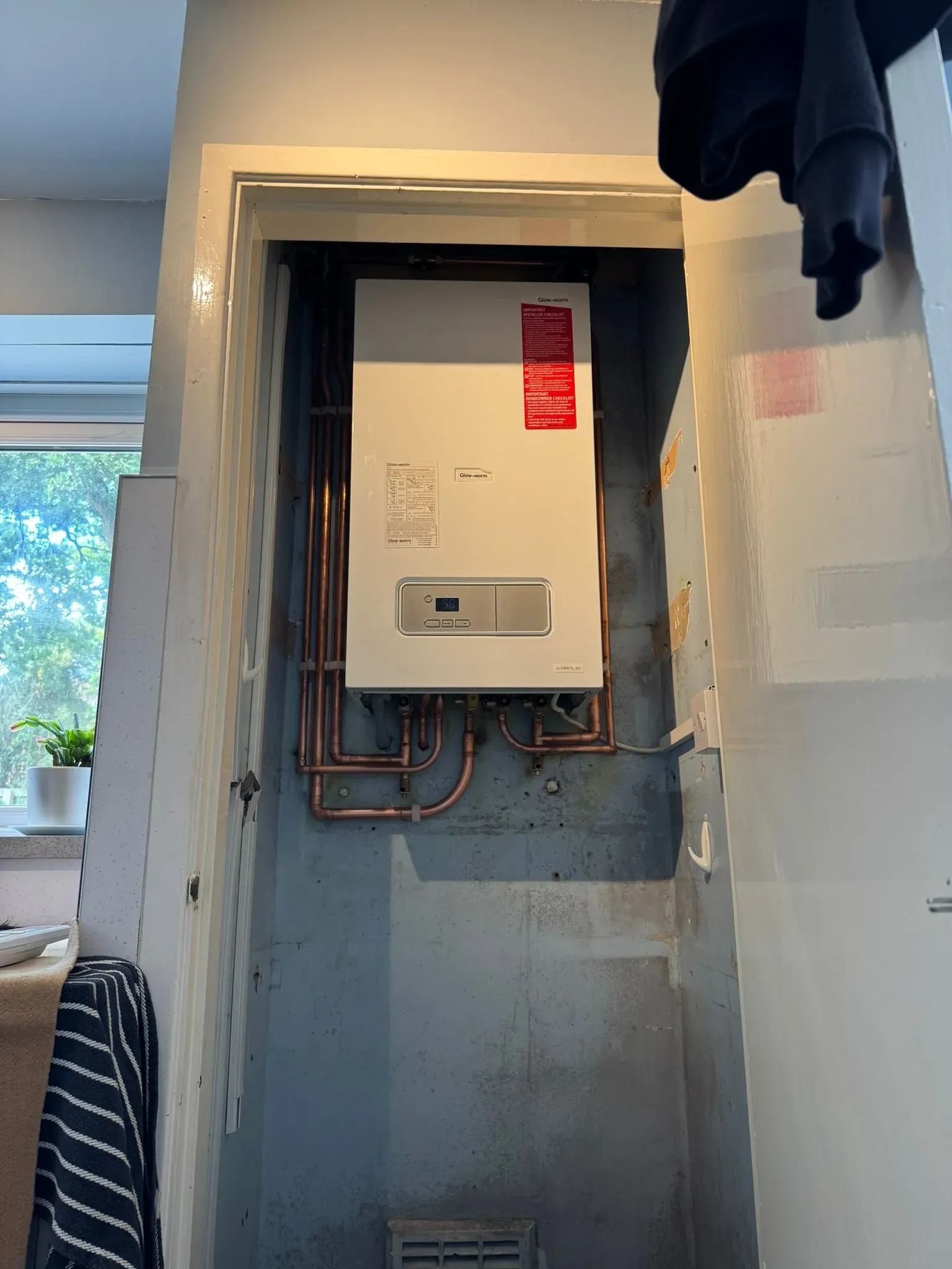 A new Glow-worm boiler installation with copper piping in a residential cupboard