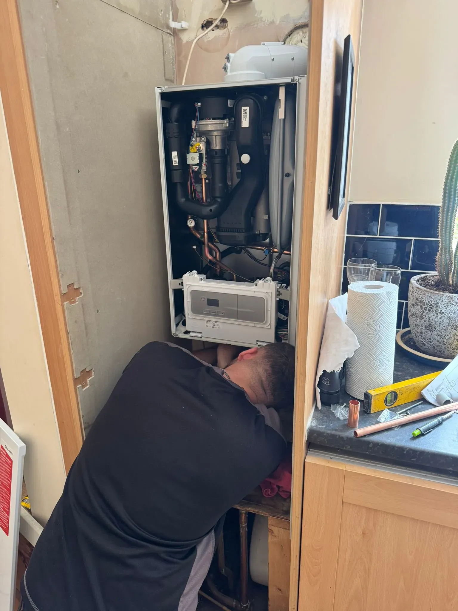 A heating engineer performing boiler repairs and maintenance on a domestic boiler in a Warrington home.