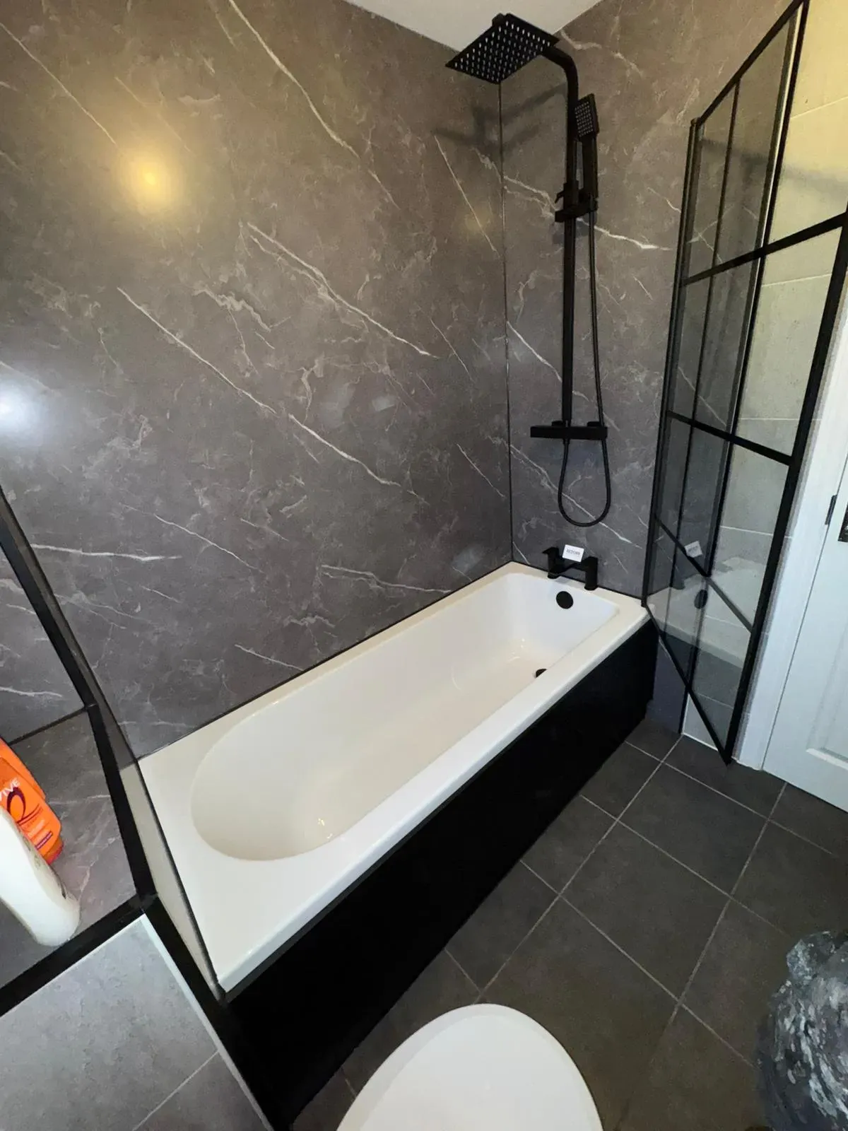 Modern bathroom installation with grey marble wall panels and black shower fixtures by Redorr Heating & Cooling Services Ltd.